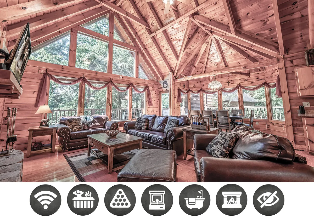 The image showcases a warm, inviting cabin interior with soaring wooden beams, expansive windows overlooking the Smoky Mountains, and a cozy seating area arranged around a glowing fireplace. Decorative lighting adds to the ambiance, setting the perfect stage for family gatherings, relaxation, and cherished moments together.