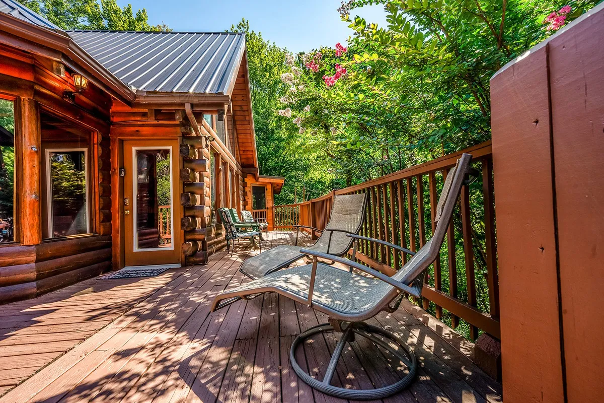 This image features the log cabin’s exterior nestled among lush greenery, with deck chairs inviting guests to relax and soak in the peaceful outdoors. The setting suggests privacy, tranquility, and a strong connection to nature—ideal for couples seeking a romantic retreat.