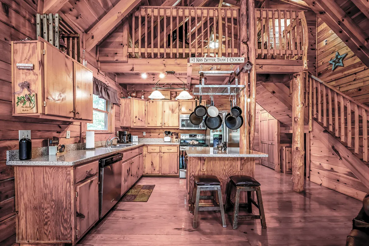 A well-appointed kitchen featuring wooden cabinetry, a granite countertop, a kitchen island with stools, and hanging pots overhead. The kitchen feels welcoming and ready for culinary adventures, making it ideal for both casual breakfasts and celebratory dinners.